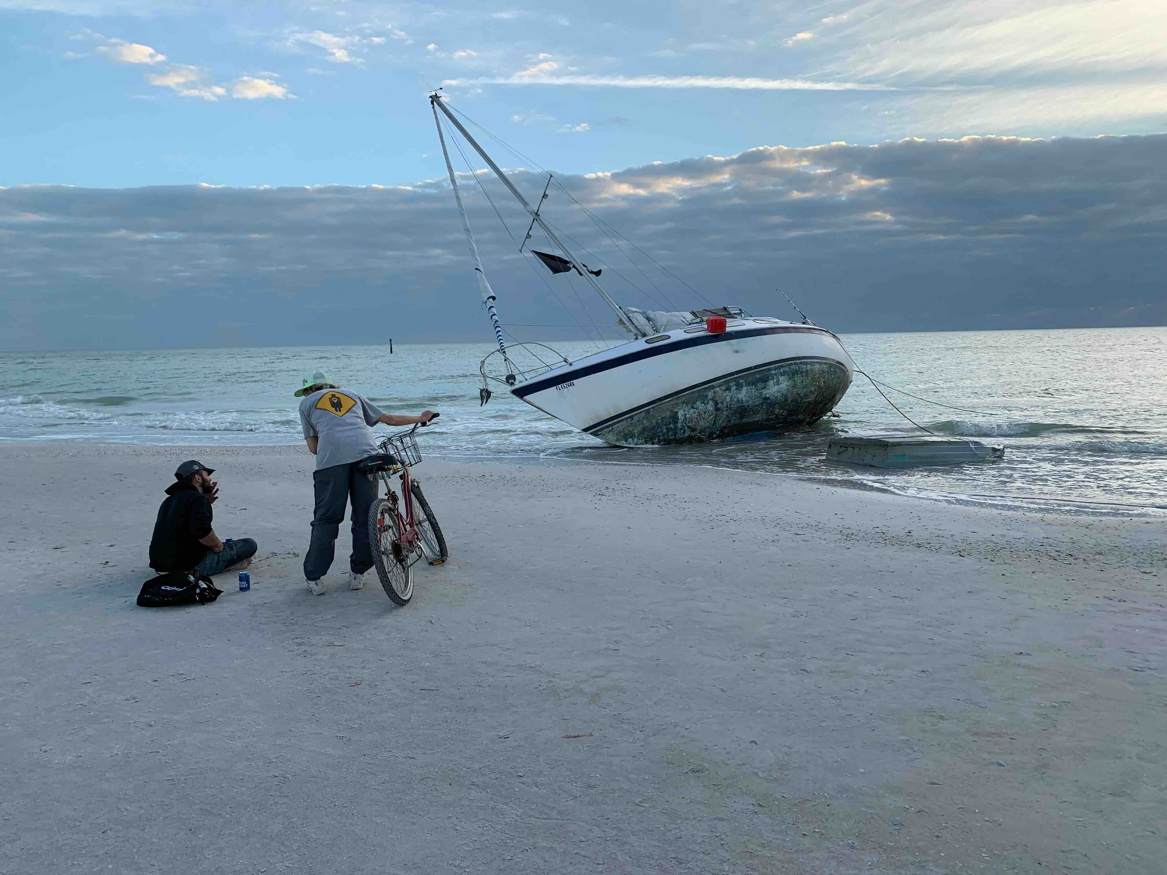 Abandoned sailboat and Marcia talking to someone watching it.